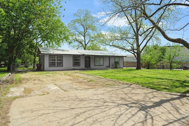 ranch-style home featuring fence, driveway, a front yard, and metal roof