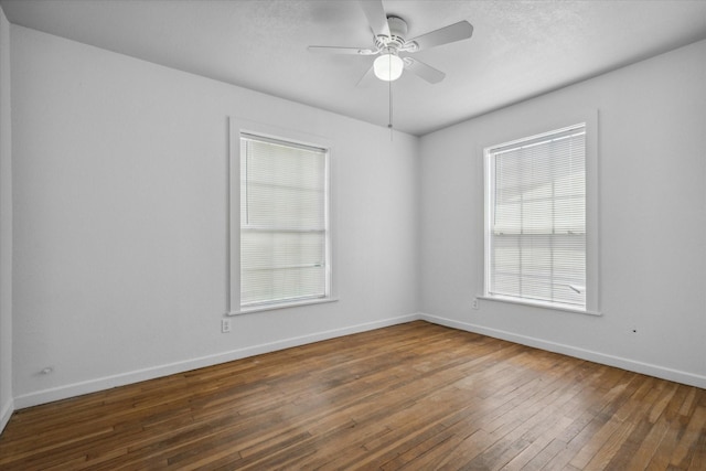 empty room featuring a ceiling fan, baseboards, a healthy amount of sunlight, and hardwood / wood-style floors