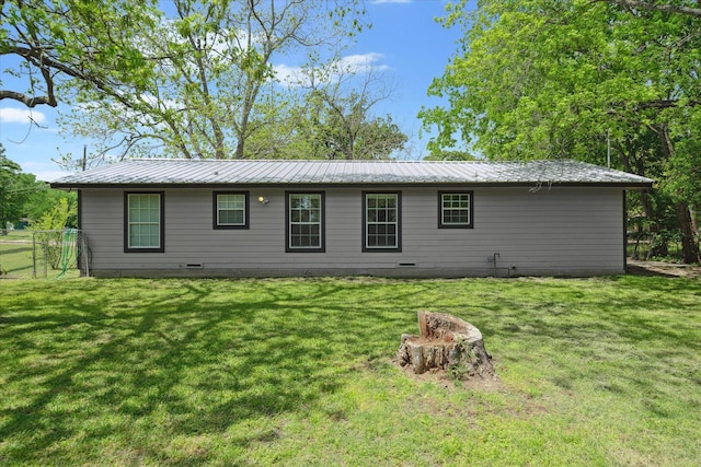 rear view of house featuring crawl space, a yard, and metal roof