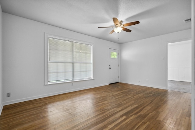 unfurnished room featuring baseboards, visible vents, a ceiling fan, and dark wood-style floors