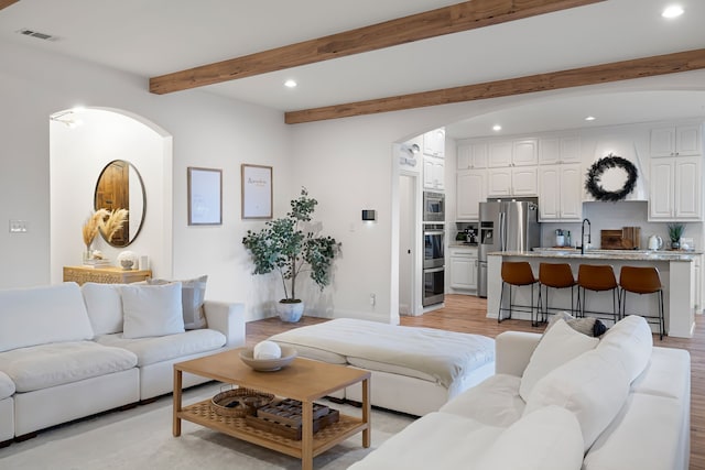 230 Heatherstone Dr, Midlothian, TX 76065 - living room featuring arched walkways, recessed lighting, beam ceiling, light wood finished floors, and baseboards