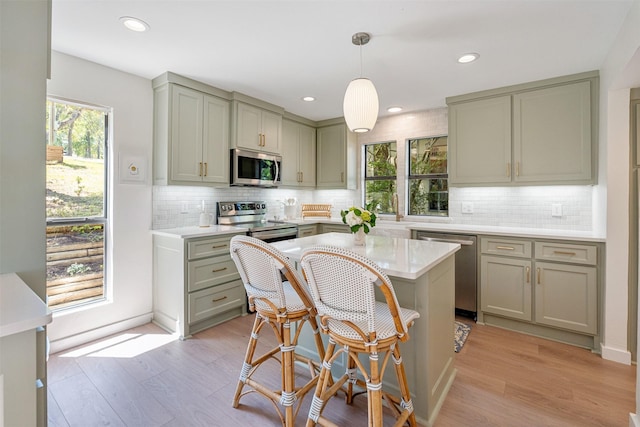 kitchen featuring decorative backsplash, light wood finished floors, light countertops, appliances with stainless steel finishes, and gray cabinetry