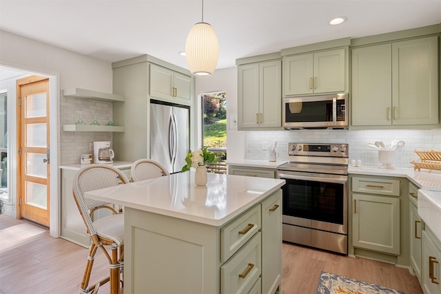 kitchen featuring stainless steel appliances, backsplash, light countertops, a breakfast bar, and green cabinets