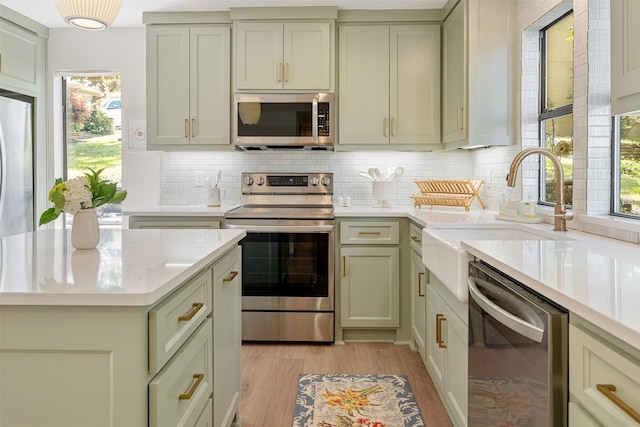 kitchen featuring tasteful backsplash, stainless steel appliances, light countertops, and a sink