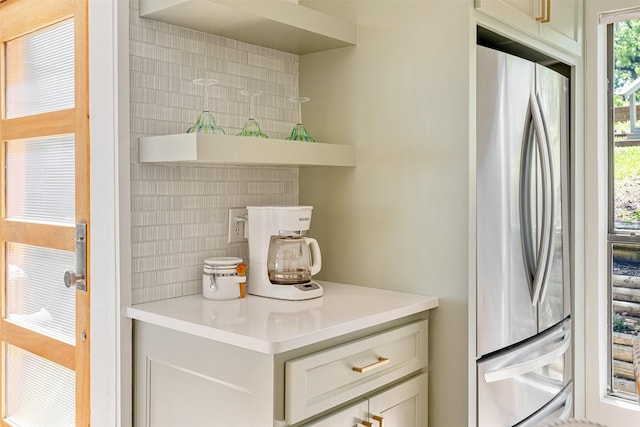 kitchen featuring light countertops, freestanding refrigerator, and tasteful backsplash