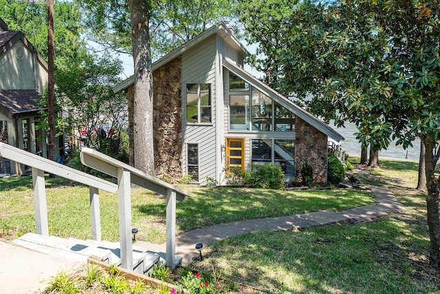 view of side of home with a lawn, a sunroom, and stone siding