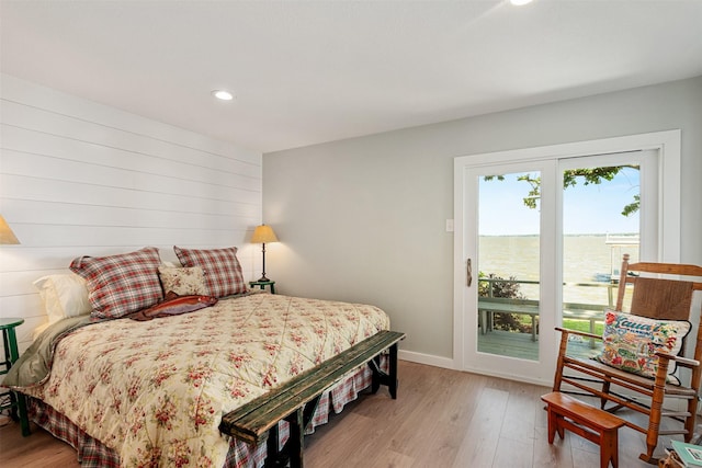 bedroom with a water view, light wood finished floors, baseboards, access to outside, and recessed lighting