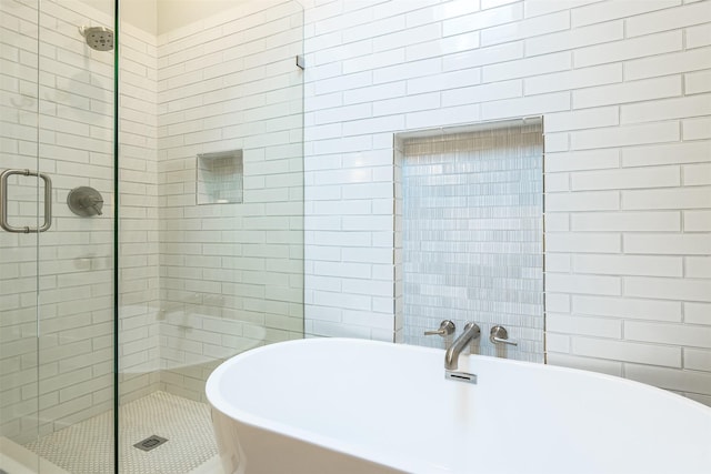 bathroom featuring a shower stall, a soaking tub, and tile walls