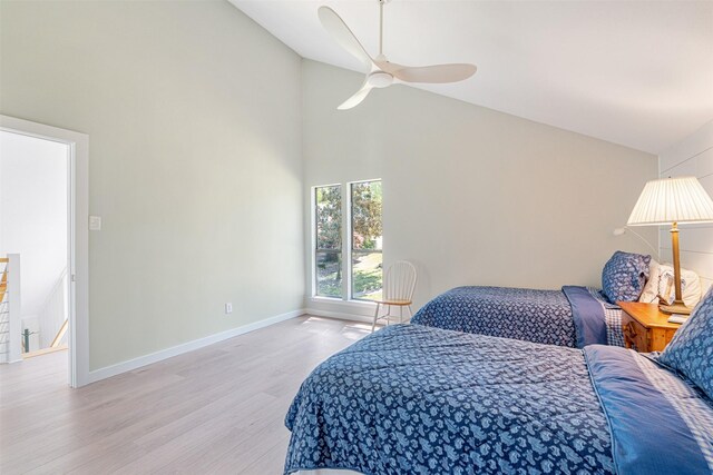 bedroom with baseboards, light wood finished floors, high vaulted ceiling, and ceiling fan