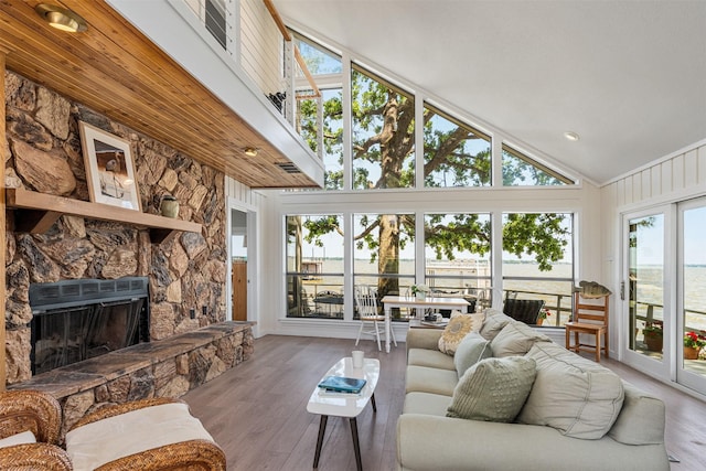 living room featuring wood finished floors, a fireplace, and high vaulted ceiling