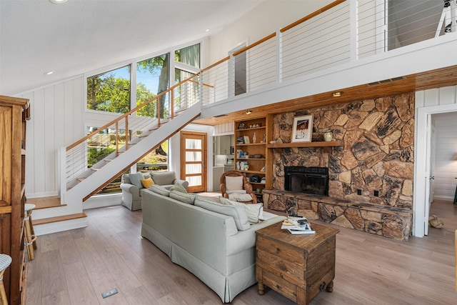 living room featuring baseboards, wood finished floors, a high ceiling, stairway, and a fireplace