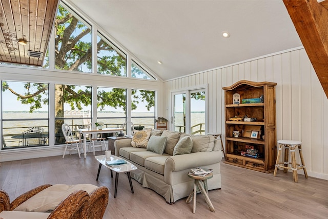 living room featuring vaulted ceiling, wood finished floors, wooden walls, and a water view