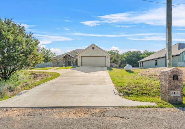 4114 Seminole Trl, Granbury, TX 76048 - view of front of home with concrete driveway, a garage, stone siding, and fence
