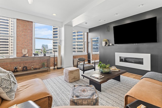 living area featuring recessed lighting, a glass covered fireplace, wood finished floors, and baseboards