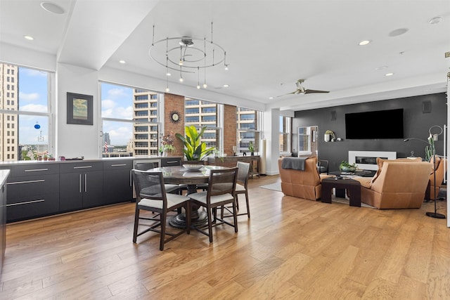 dining room featuring light wood finished floors, a view of city, recessed lighting, and ceiling fan