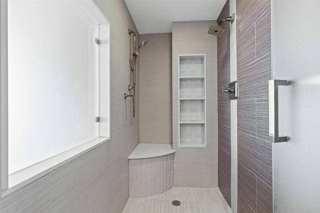 bathroom featuring tile walls and a tile shower