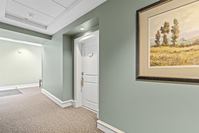corridor featuring baseboards and carpet flooring