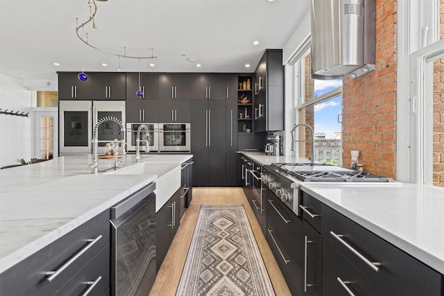 kitchen with beverage cooler, dark cabinetry, wall chimney exhaust hood, light wood-style flooring, and appliances with stainless steel finishes