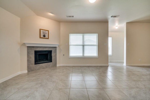 unfurnished living room featuring a tiled fireplace, visible vents, light tile patterned floors, and baseboards