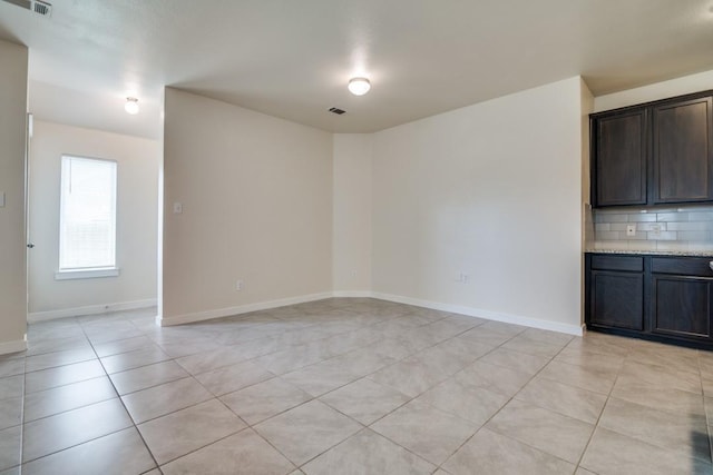 interior space featuring light tile patterned floors, visible vents, and baseboards