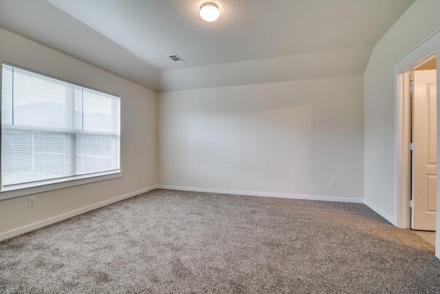 carpeted empty room featuring visible vents, vaulted ceiling, and baseboards