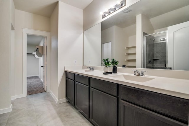 full bath with a sink, a shower stall, tile patterned floors, double vanity, and baseboards
