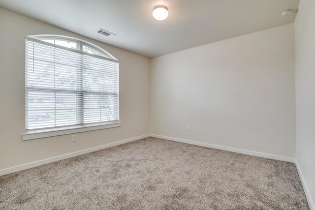 carpeted empty room featuring a healthy amount of sunlight, visible vents, and baseboards
