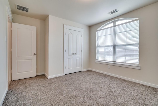 unfurnished bedroom featuring baseboards, visible vents, and carpet flooring