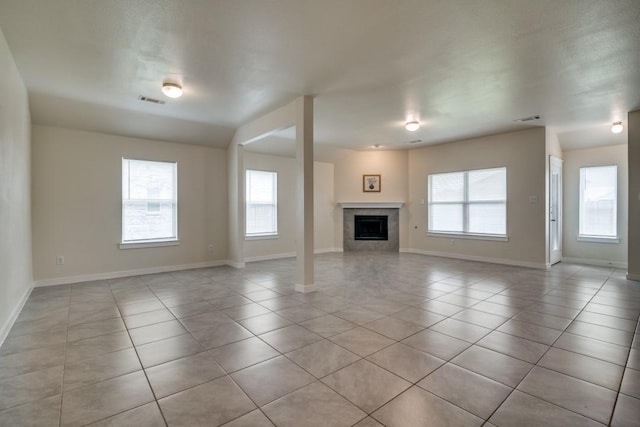 unfurnished living room with baseboards, light tile patterned flooring, a fireplace, and plenty of natural light