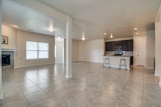 unfurnished living room with recessed lighting, a tiled fireplace, light tile patterned floors, visible vents, and baseboards