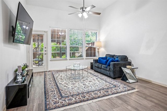 living room with baseboards, a ceiling fan, wood finished floors, and high vaulted ceiling