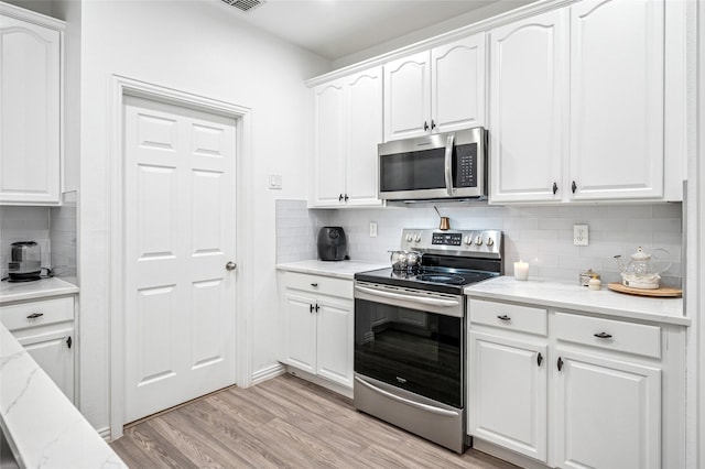 kitchen featuring light wood-style flooring, white cabinetry, appliances with stainless steel finishes, and decorative backsplash