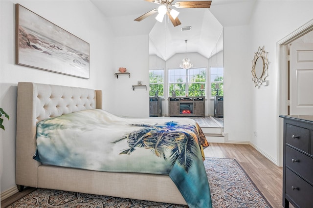 bedroom featuring vaulted ceiling, visible vents, baseboards, ceiling fan with notable chandelier, and wood finished floors