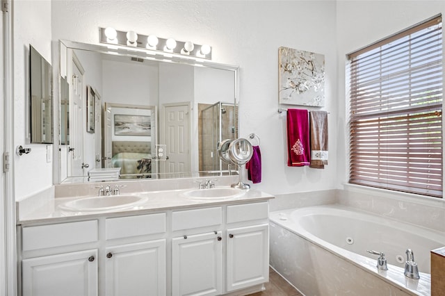 ensuite bathroom featuring a whirlpool tub, ensuite bath, a stall shower, and a sink