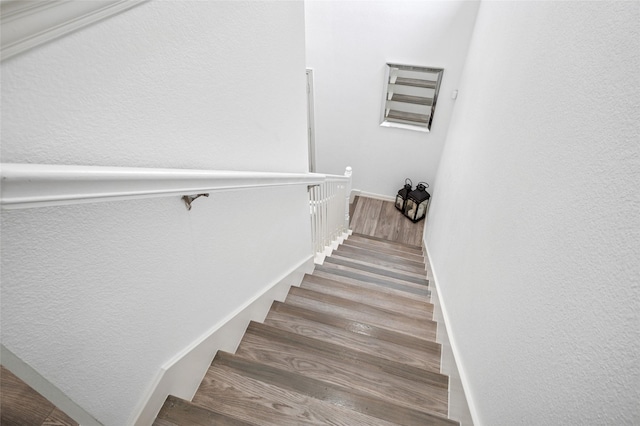 stairs featuring a textured wall and wood finished floors
