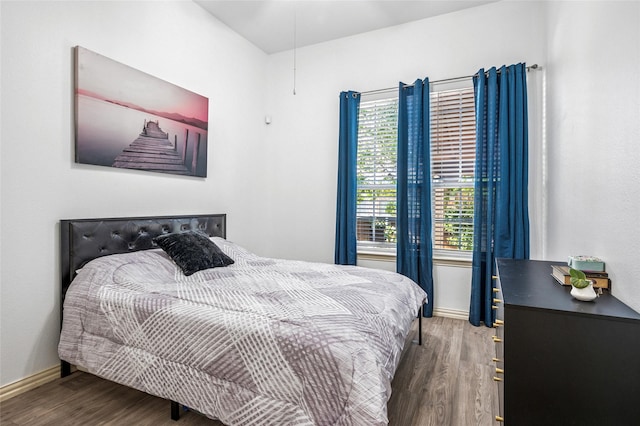 bedroom with baseboards, wood finished floors, and multiple windows