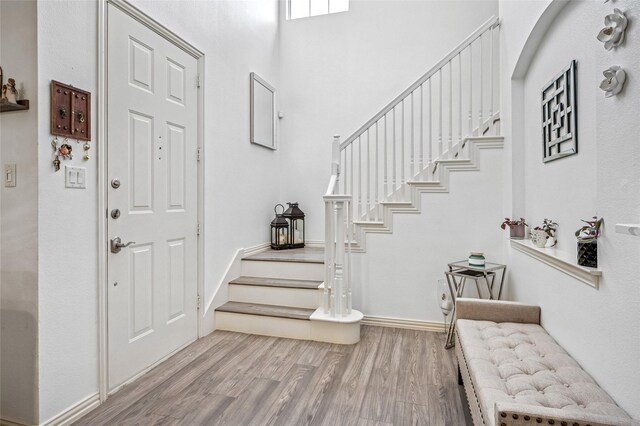 foyer entrance featuring baseboards, wood finished floors, and stairs