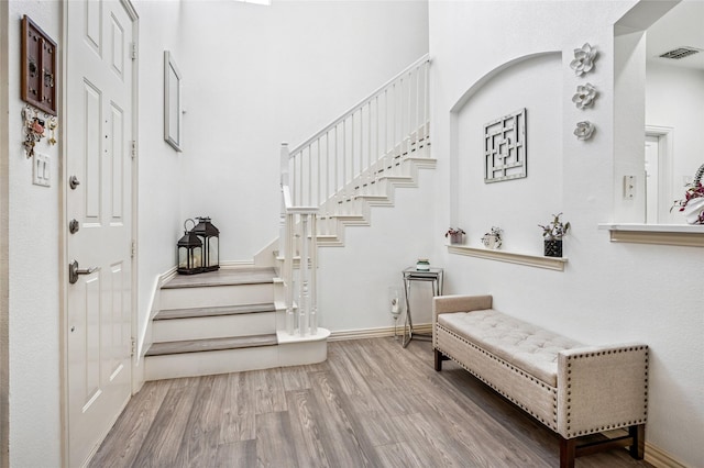 entrance foyer with baseboards, wood finished floors, visible vents, and stairway