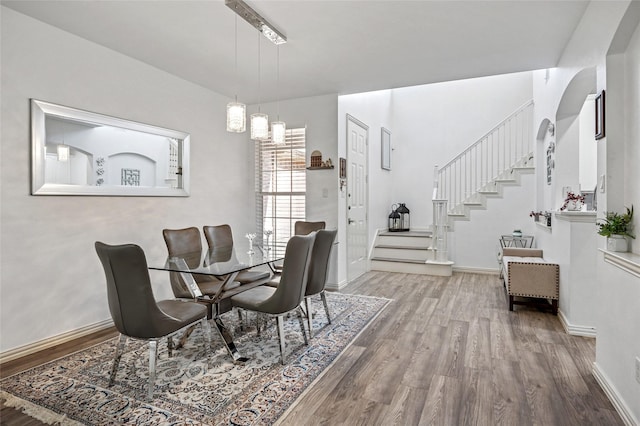 dining space with baseboards, wood finished floors, and stairs