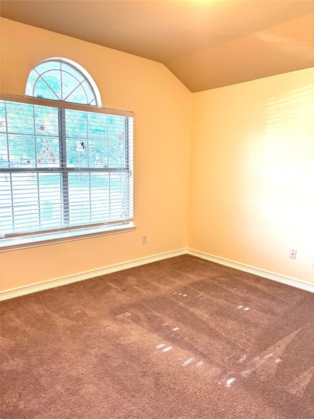 carpeted spare room with lofted ceiling and baseboards
