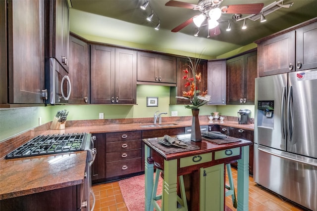 5713 Pershing Ave, Fort Worth, TX 76107 - kitchen with dark brown cabinets, a sink, track lighting, ceiling fan, and stainless steel appliances