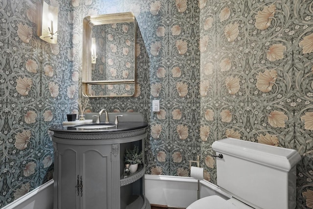 bathroom with vanity, toilet, and wallpapered walls