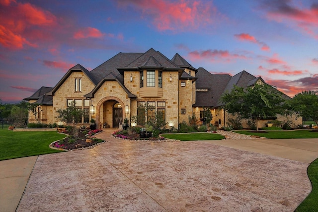 french country style house featuring a front yard, brick siding, and stone siding