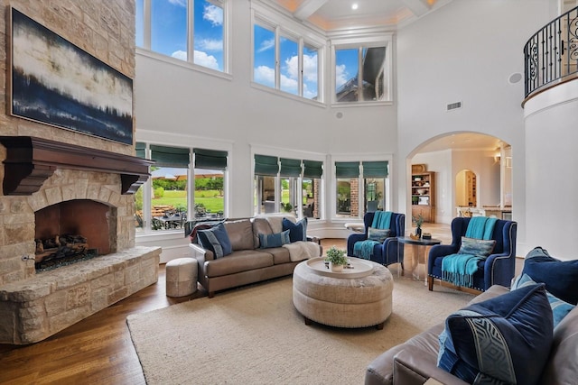 living room featuring a high ceiling, visible vents, a healthy amount of sunlight, and hardwood / wood-style flooring