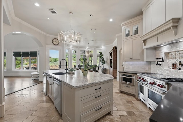 kitchen featuring a sink, arched walkways, stainless steel appliances, decorative backsplash, and ornamental molding