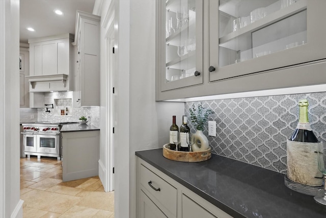 bar with stone tile flooring, decorative backsplash, custom exhaust hood, recessed lighting, and double oven range