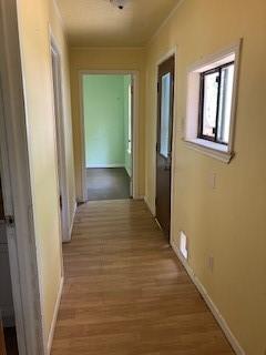 hallway featuring baseboards and wood finished floors