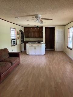 unfurnished living room featuring light wood-style flooring, a textured ceiling, and ceiling fan