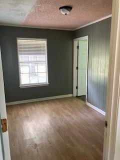 spare room featuring baseboards, wood finished floors, and a textured ceiling