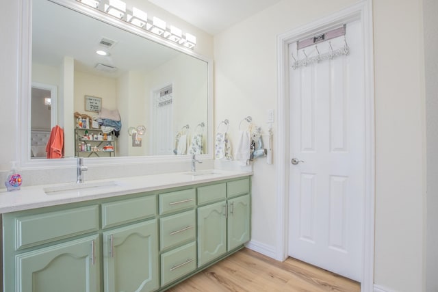 full bathroom featuring wood finished floors, a sink, visible vents, and double vanity